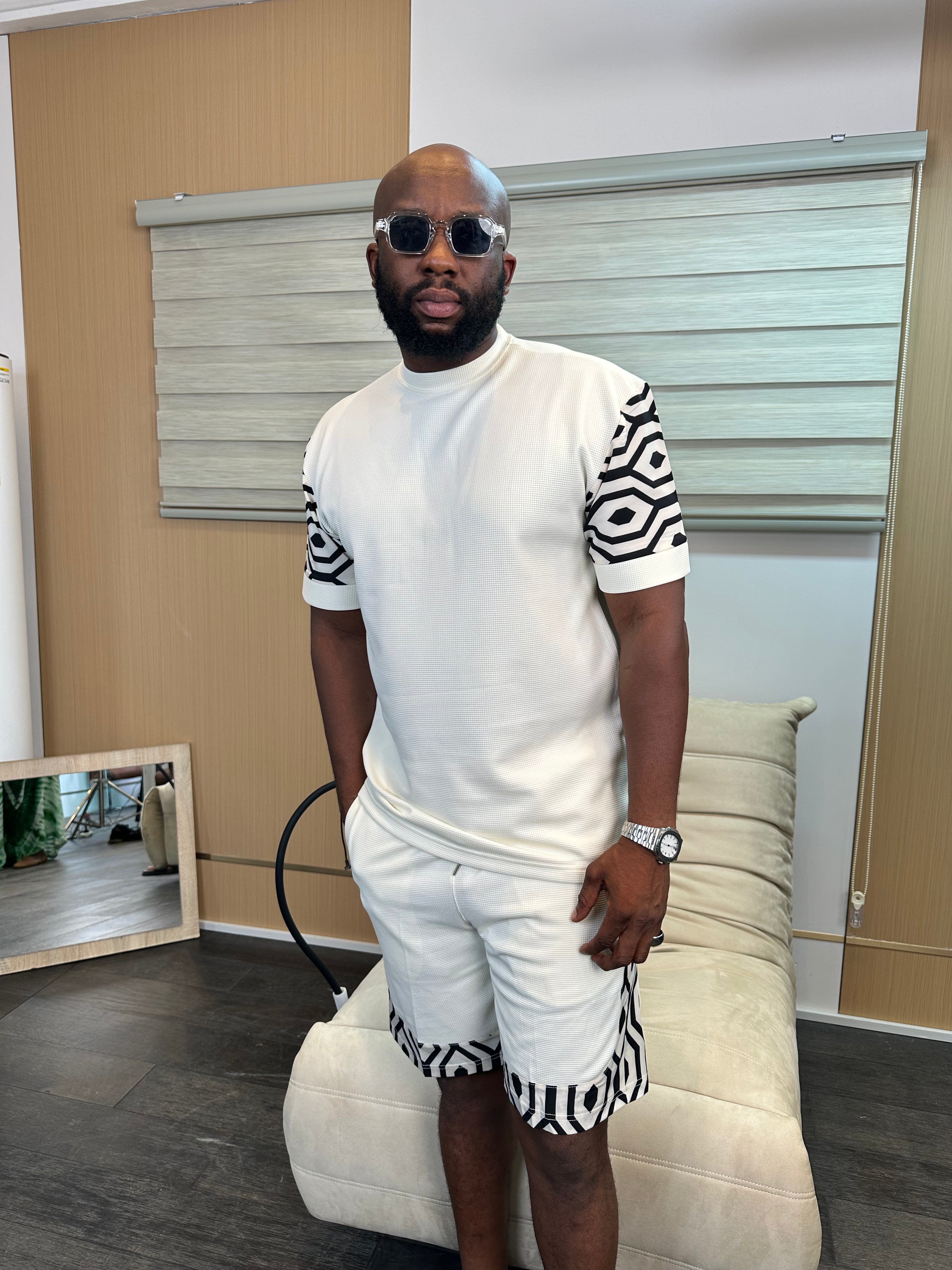 Man wearing a white textured two-piece co-ord shorts set with black patterned sleeve and hem details by Perfect Mann