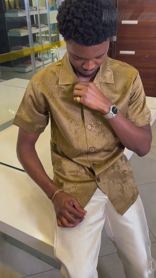 Man wearing a bronze jacquard short-sleeve shirt with ivory tailored trousers from Perfect Mann's premium two-piece occasion collection vide